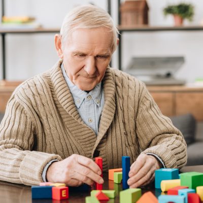 senior man playing with wooden toys at home